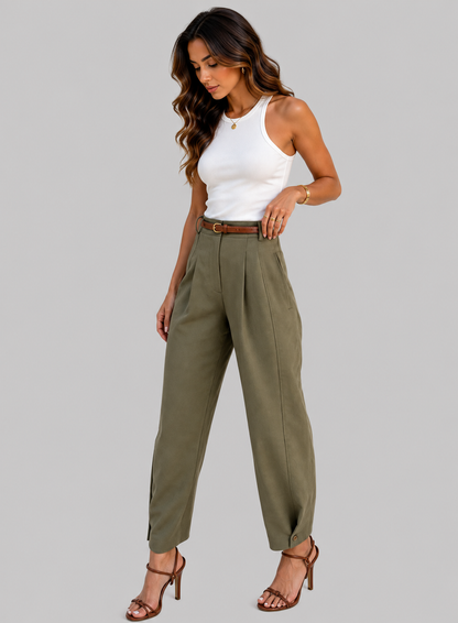 A woman modeling high-waisted olive green wide-leg trousers with a brown belt, paired with a white tank top and brown strappy heels, against a solid gray background.