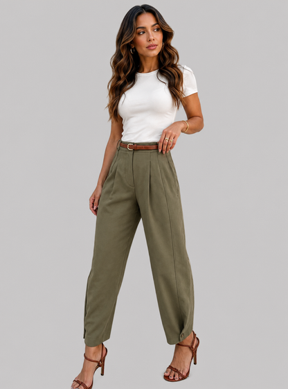 A woman modeling high-waisted olive green wide-leg trousers with a brown belt, styled with a white t-shirt and brown strappy heels, against a solid gray background.