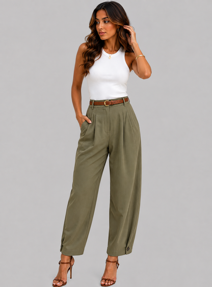 A woman modeling high-waisted, wide-leg olive green pants with a brown belt, paired with a white sleeveless top and brown strappy heels, against a solid gray studio background.