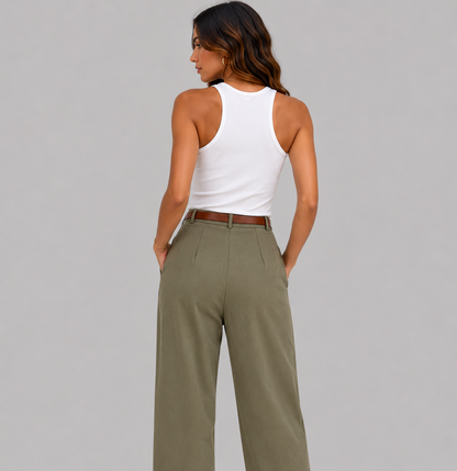 A woman shown from the back wearing high-waisted, wide-leg olive green trousers with a brown belt, paired with a white tank top and brown heeled sandals, against a solid gray studio background.