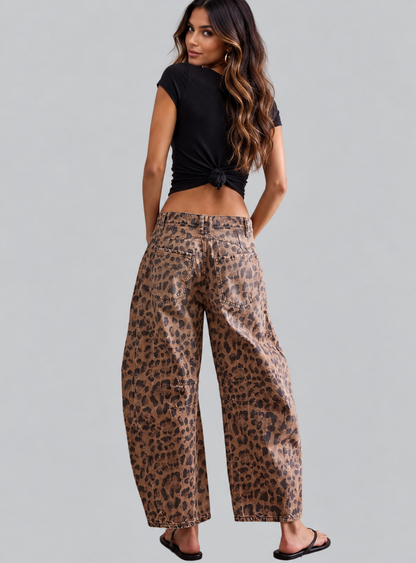 A woman shown from the back wearing leopard-print wide-leg pants and a black tied crop top, standing against a light gray studio background.
